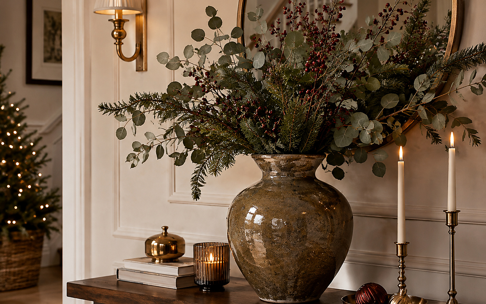 Grand vase décoratif en céramique avec branches de sapin, eucalyptus et baies rouges sur une console.