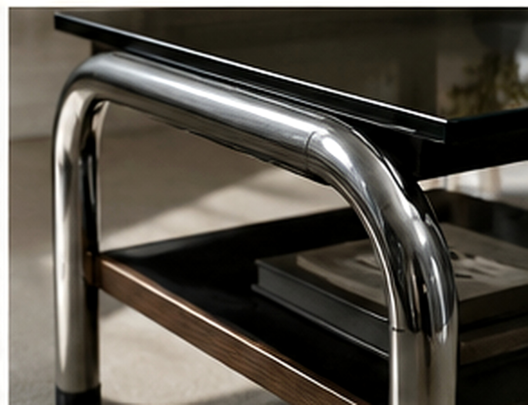 Détail de mobilier associant structure chromée et bois foncé pour un contraste froid chaud.