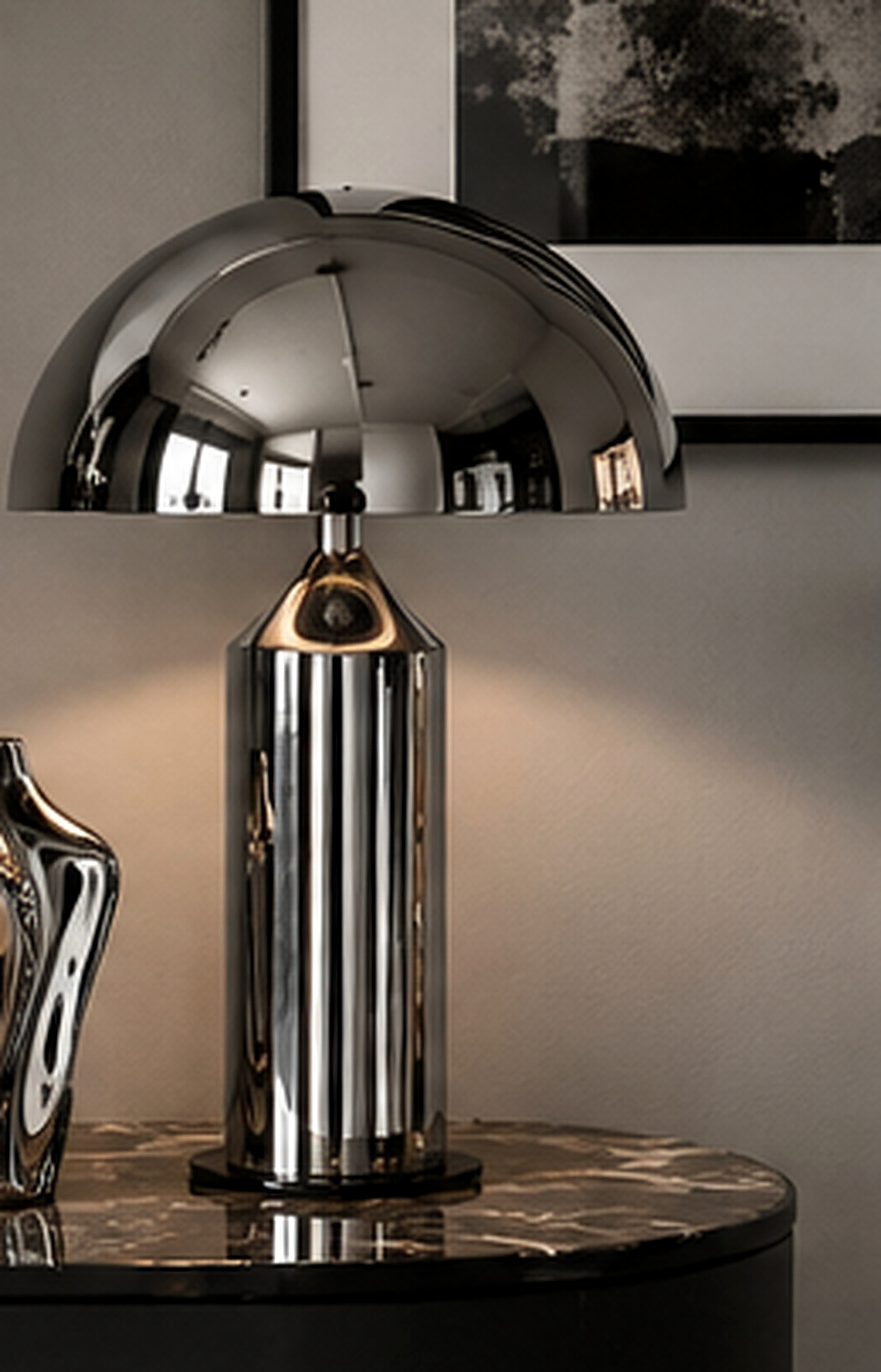 Lampe et objets décoratifs en chrome brillant sur une console sombre dans un intérieur contemporain.