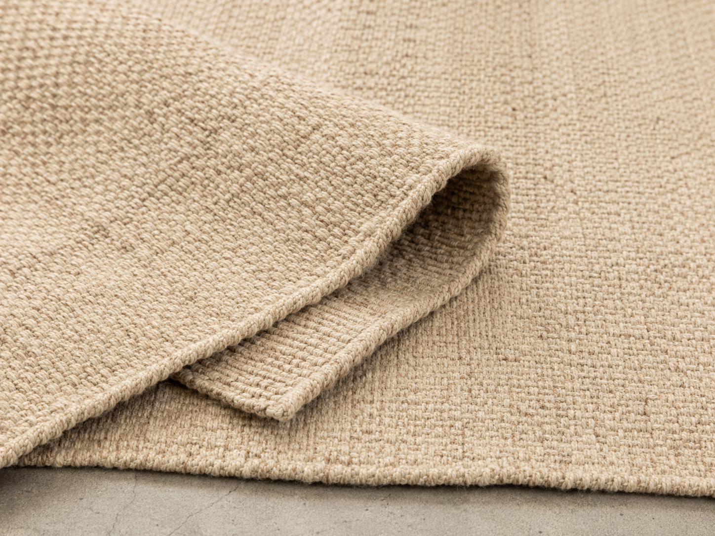 Gros plan sur un tapis tissé plat en lin ou coton dans des tons naturels.