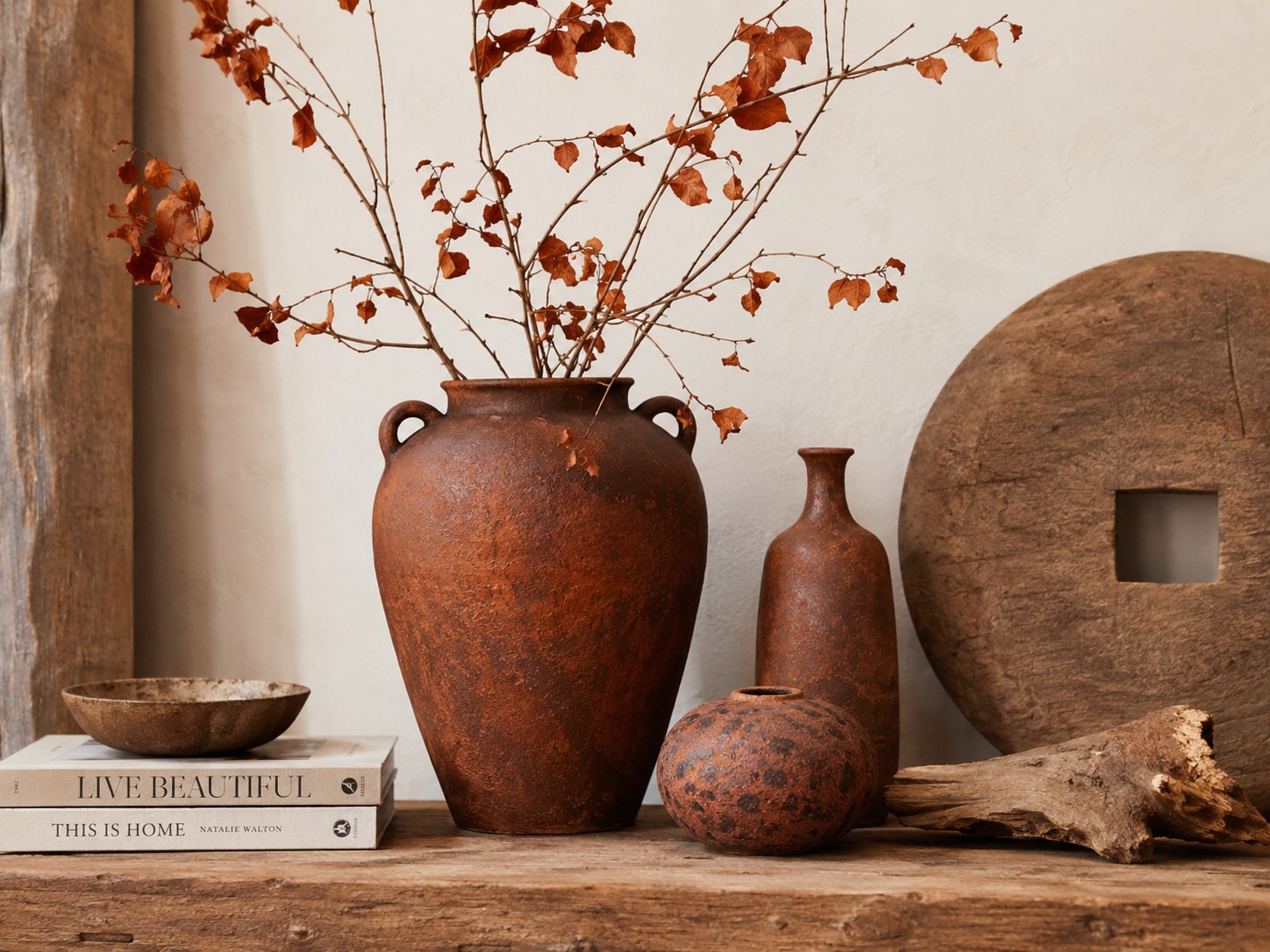 Nature morte décorative avec vases rouille, bois vieilli et branches séchées.