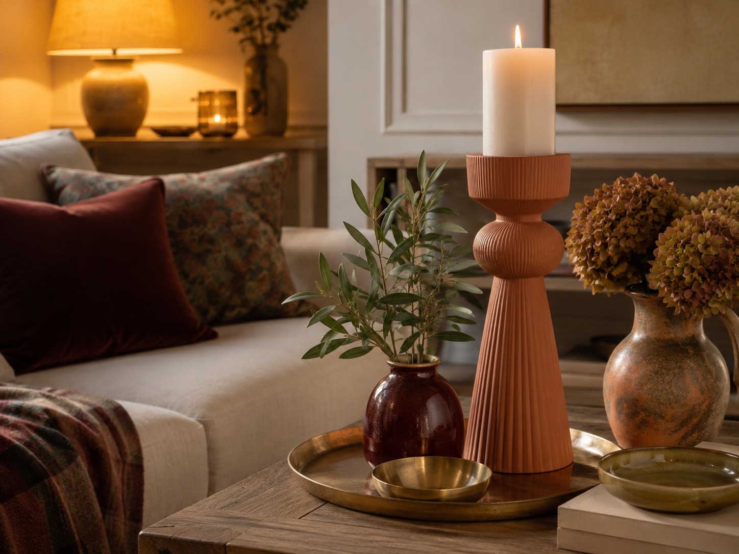 Coin salon de septembre avec bougie chaude et accents terracotta, bordeaux et vert olive.