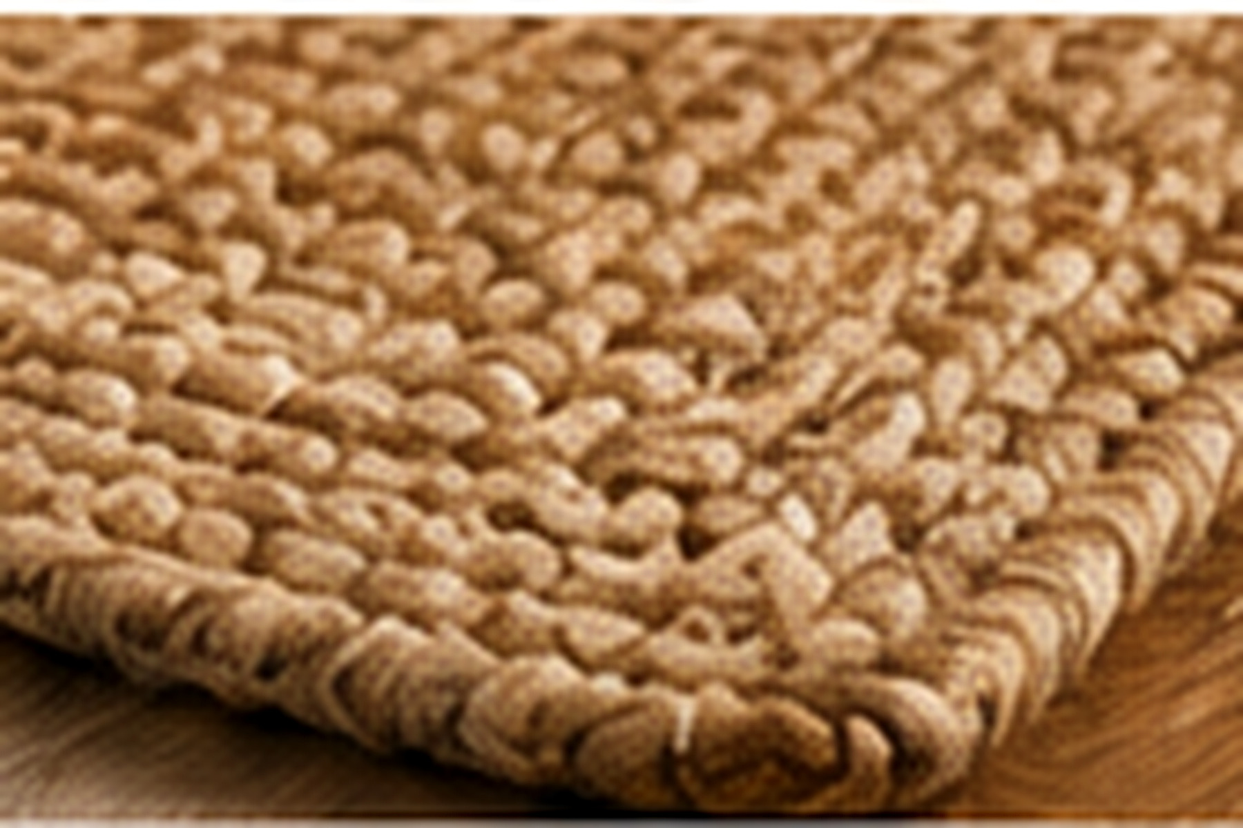 Gros plan sur les fibres naturelles tressées d’un tapis beige en jute.