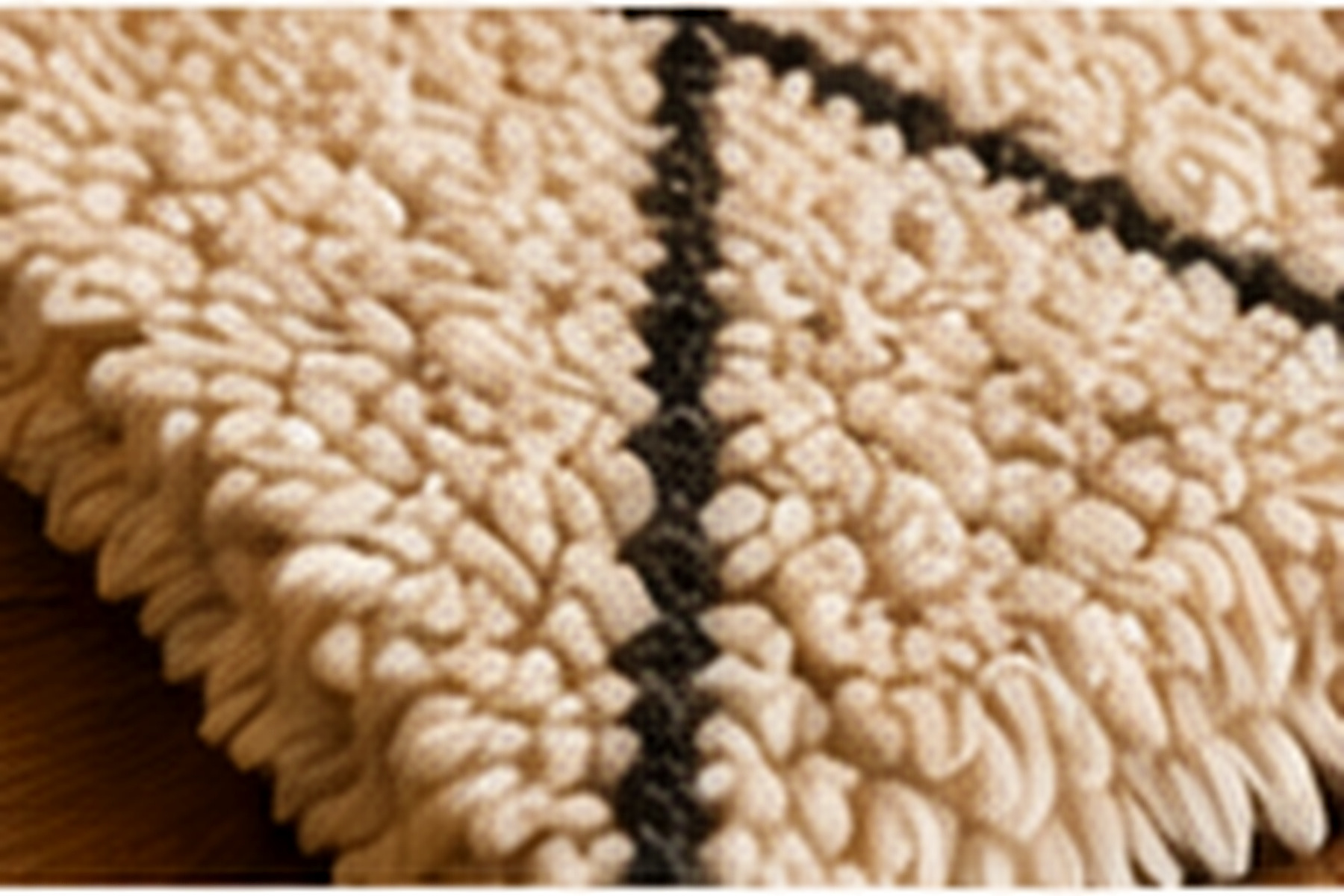 Gros plan sur la texture épaisse d’un tapis en laine claire à motif noir.