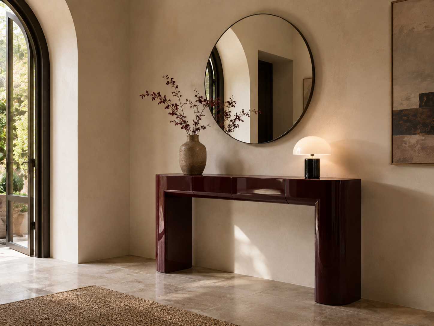 Entrée lumineuse avec console bordeaux laquée, grand miroir rond et vase en pierre.