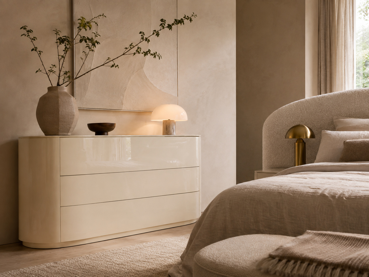 Chambre chaleureuse avec commode crème laquée aux lignes arrondies et textiles naturels.