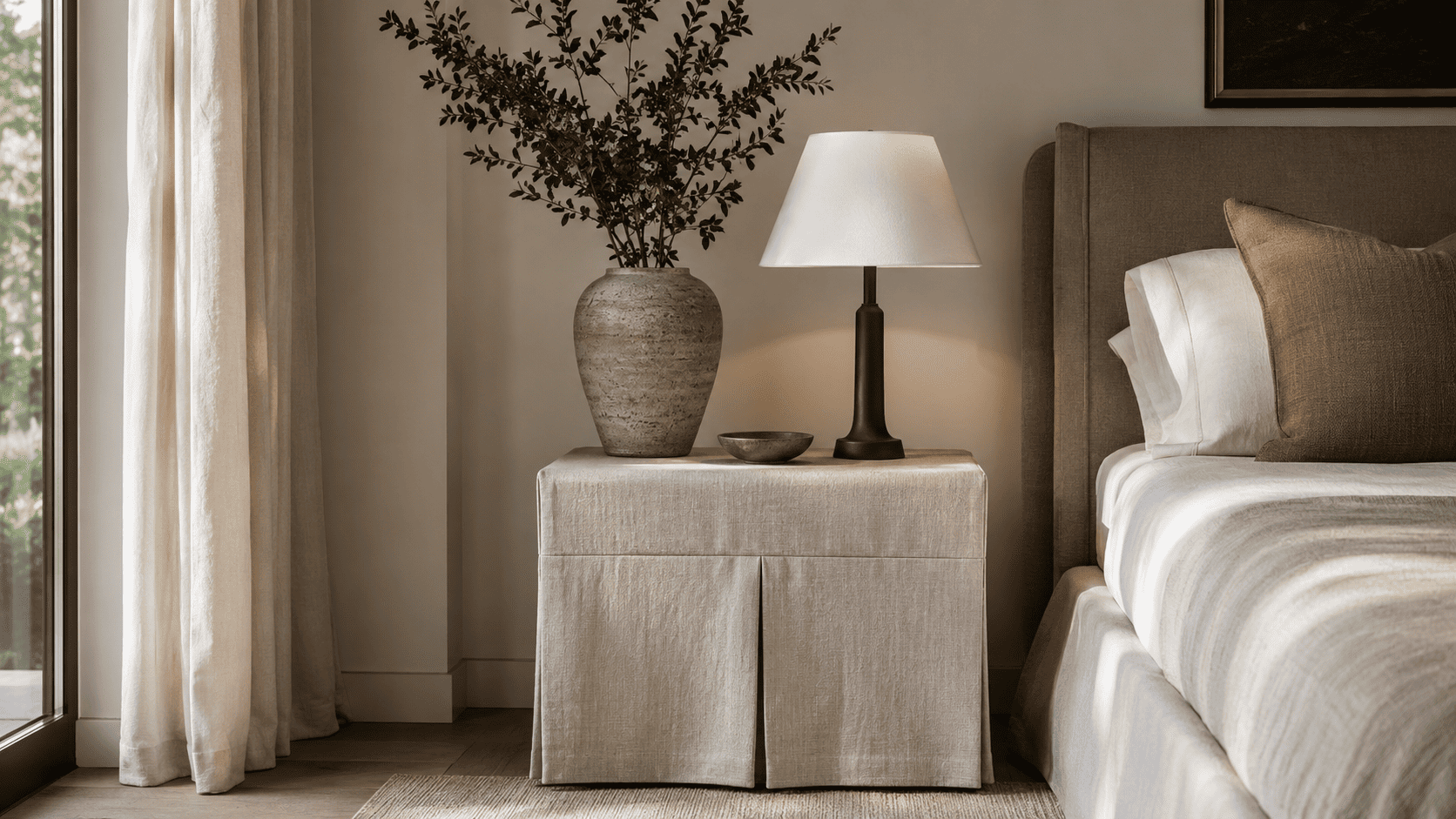 Coin chambre contemporain avec table de chevet juponnée, lampe design et textile naturel.