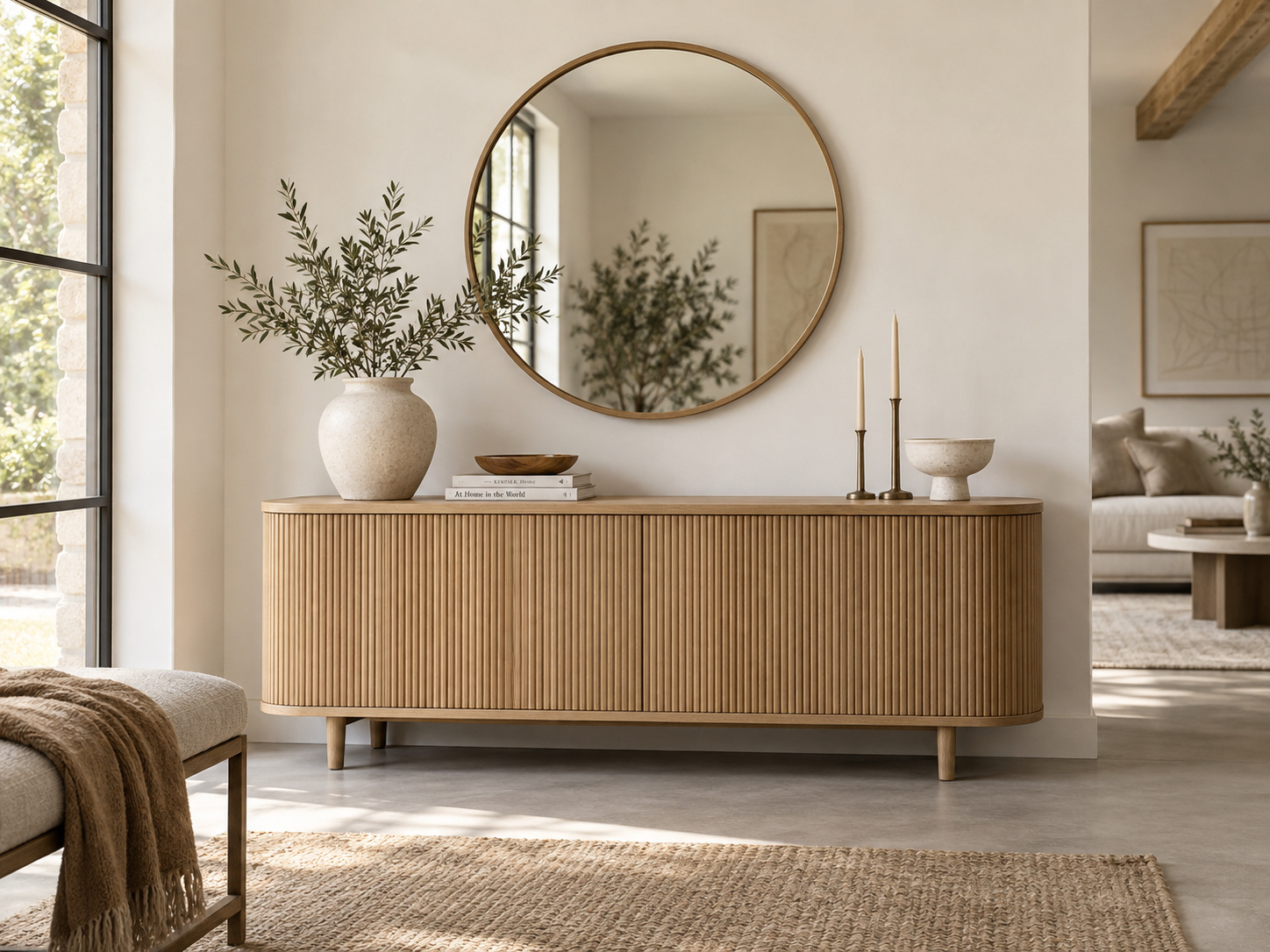 Buffet bas en bois rainuré et grand miroir rond dans un intérieur scandinave naturel.