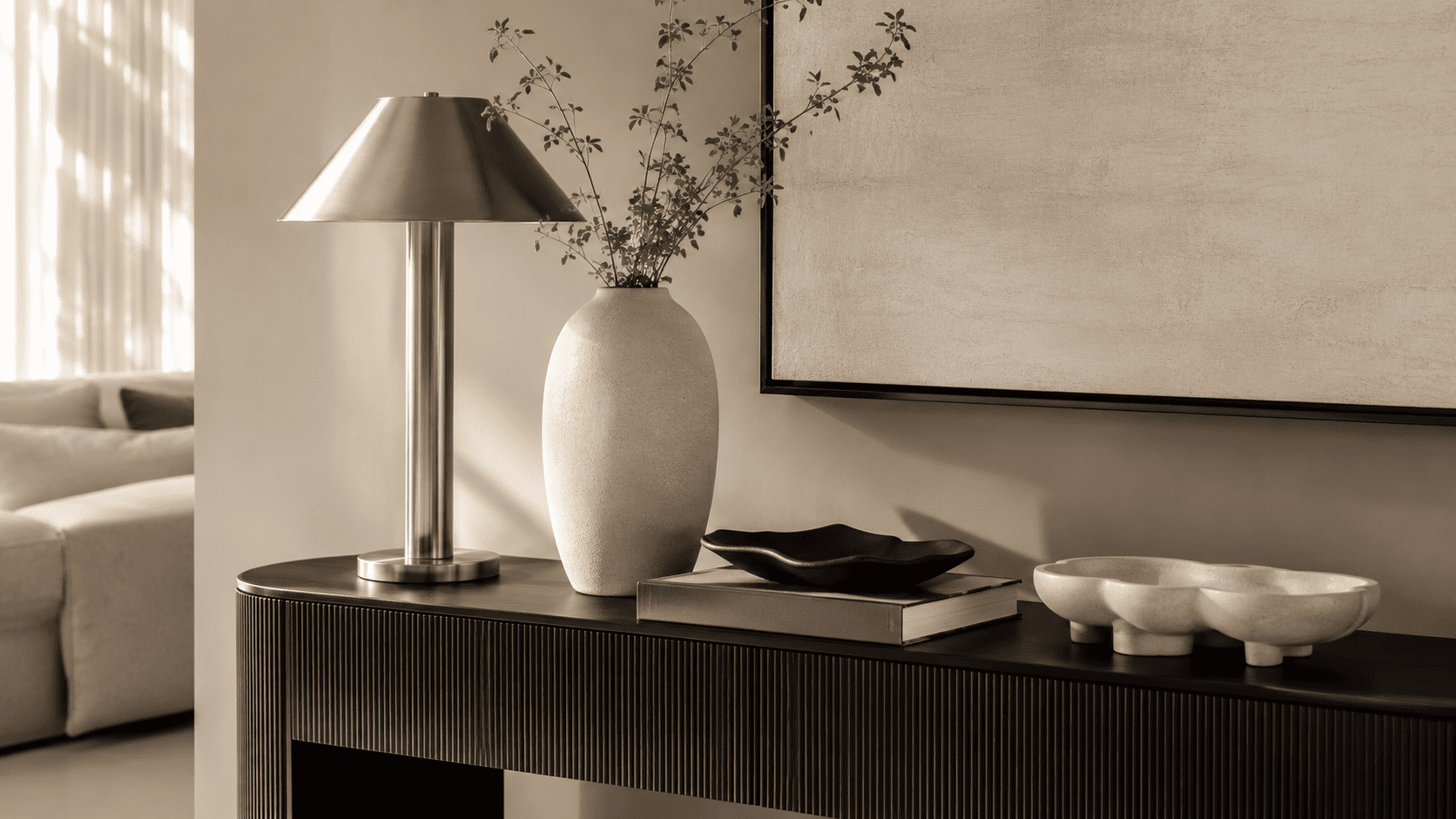 Détail de console contemporaine avec lampe en nickel satiné, vase céramique et objets déco.