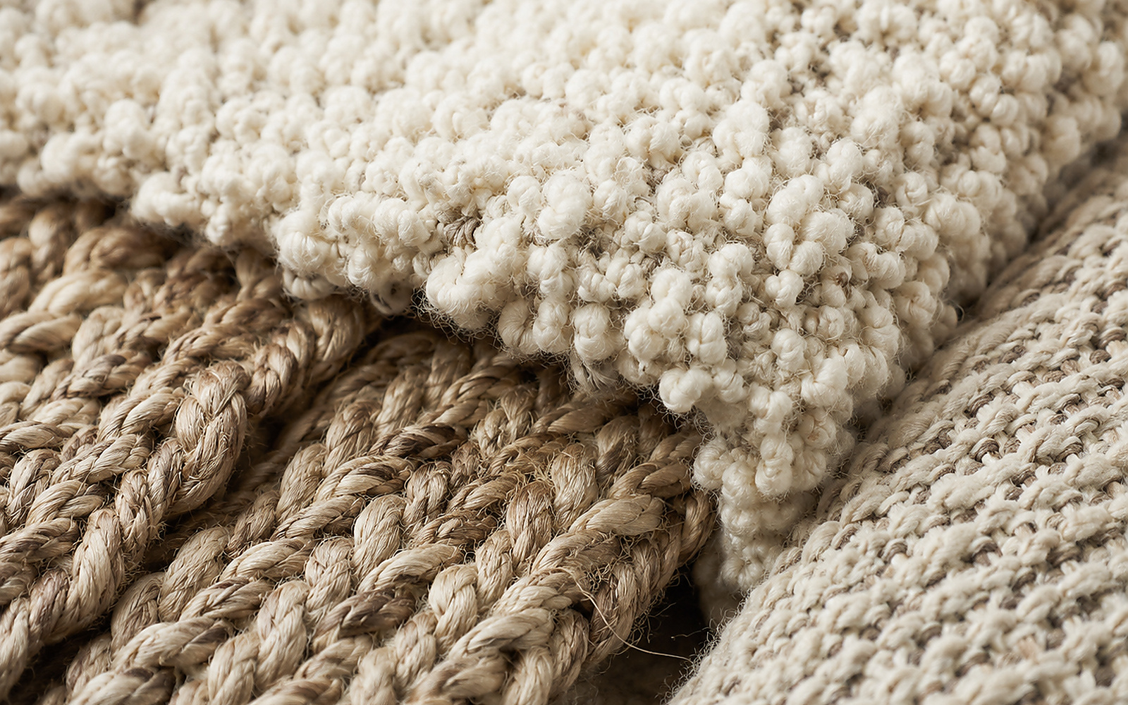 Gros plan sur laine épaisse, fibres tissées et textiles naturels aux tons crème et beige.