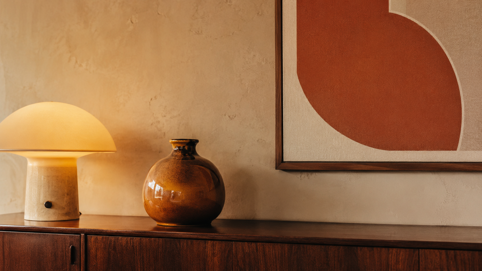 Objets déco années 70 avec lampes champignon, vases en céramique émaillée, globe ambré, coussins graphiques et bois foncé
