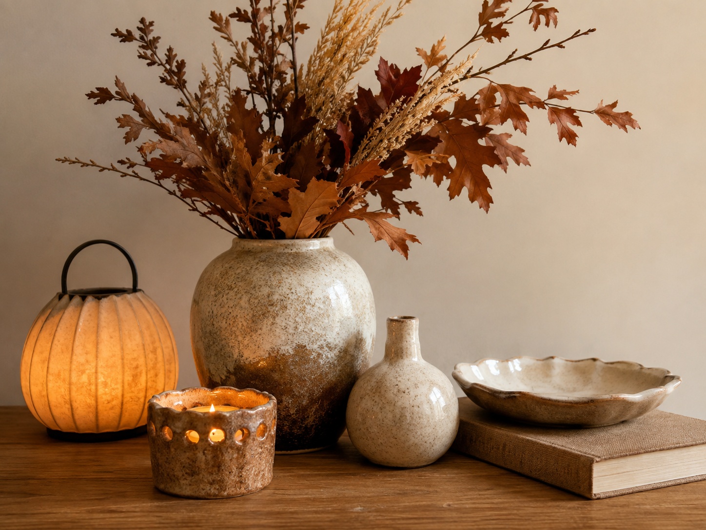 Table basse d’automne avec grand vase, branche d’automne, bougie et livre dans un salon apaisant.